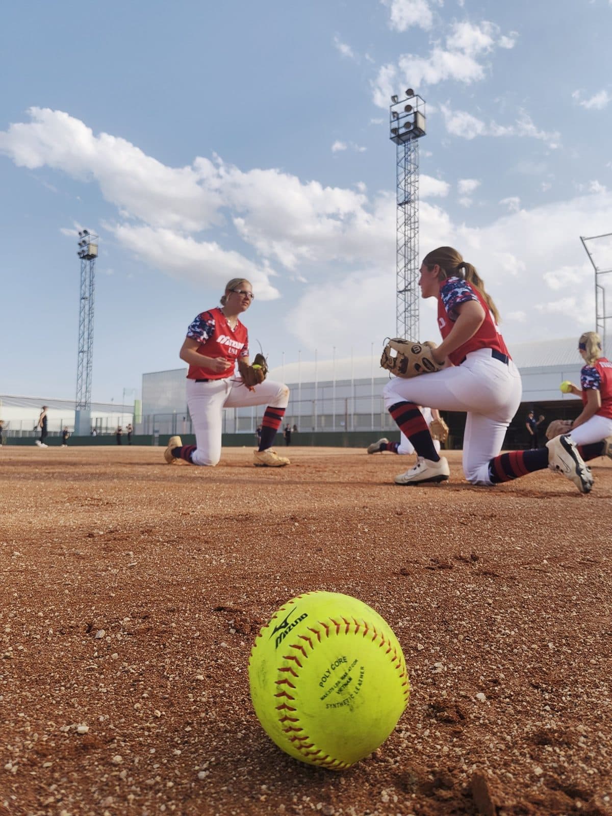A softball resting on the grass at a Spanish ballpark during an Odisea Tours softball tour