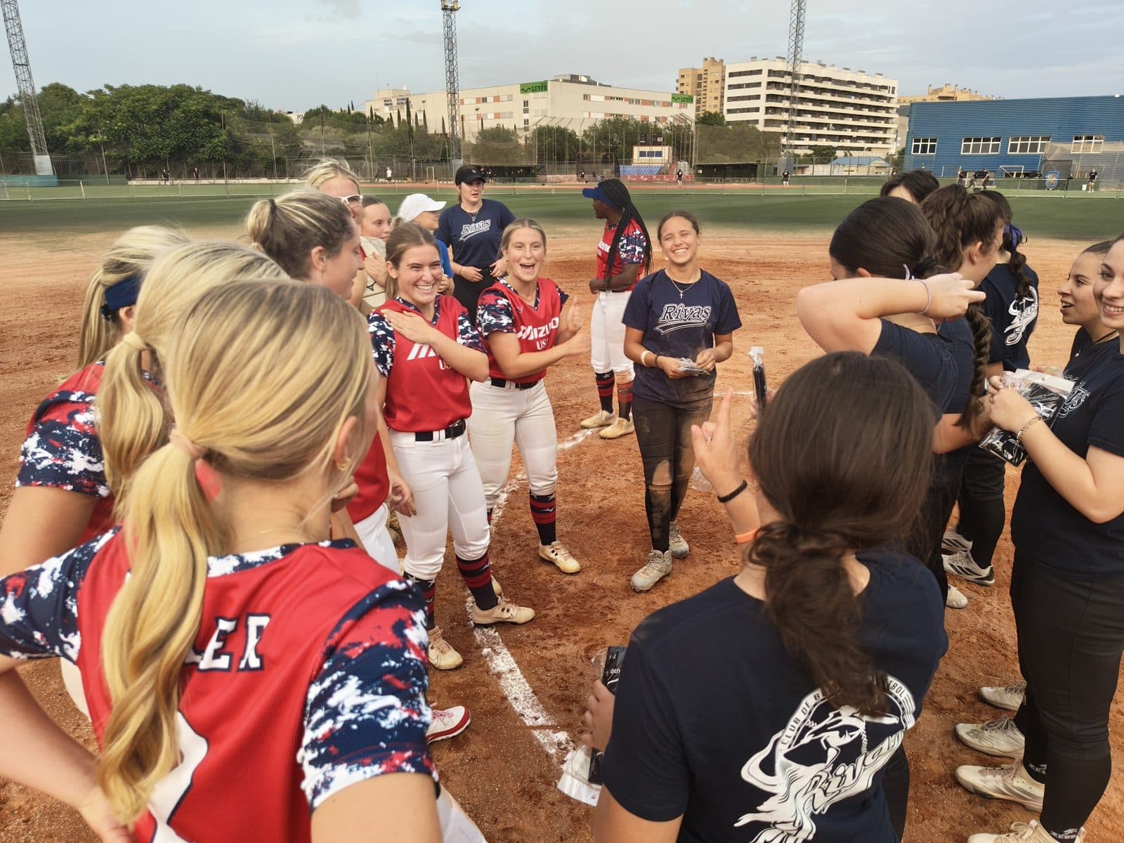 A visiting US softball team and their Spanish host club share the field on tour in Spain