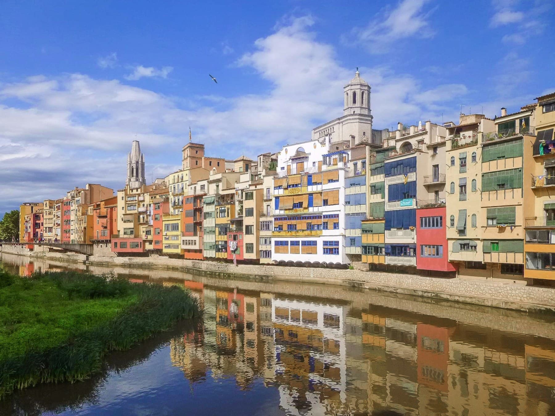 The coloured houses along the Onyar river in Girona with the cathedral bell tower behind